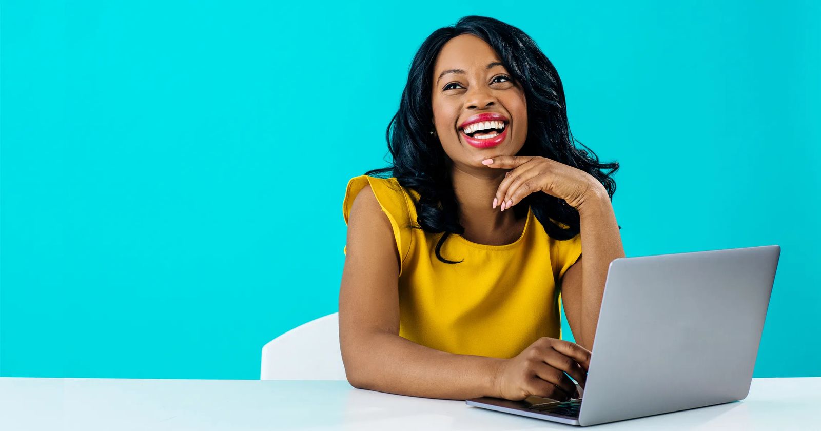 Woman smiling with laptop against blue background. Photo represents woman creating an effective homepage.