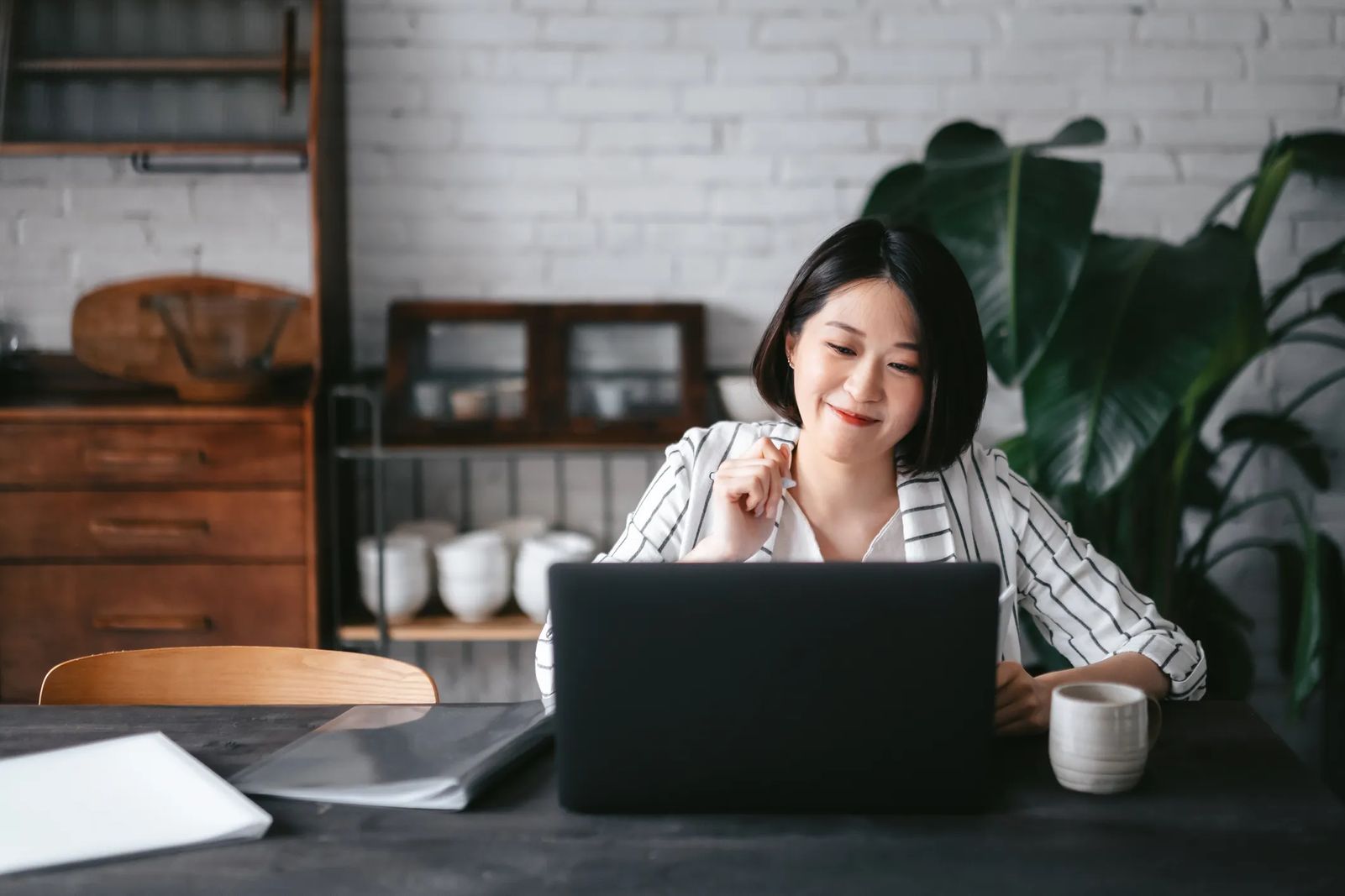 website goal setting woman looking at computer at dining table and smiling